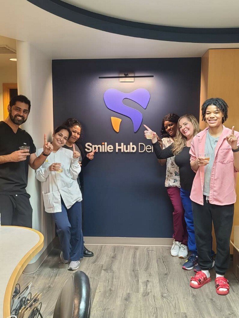 The Smile Hub Bellevue team gathered in front of the practice logo wall